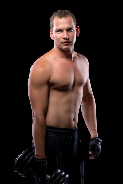 Bellissimo bodybuilder sexy con manubri su sfondo nero — Foto Stock