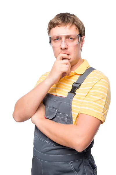 Ένας άντρας σε φόρμες και προστατευτικά γυαλιά σκέψης σχετικά με ένα λευκό bac — Φωτογραφία Αρχείου