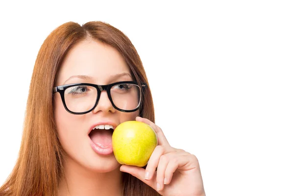 Hambrienta joven con gafas mordiendo una manzana verde en un blanco — Foto de Stock