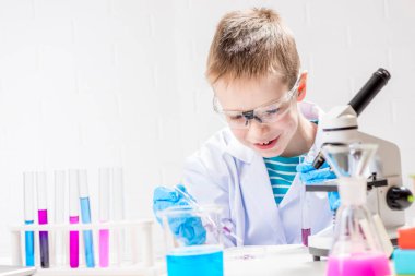 Mikroskobu olan bir öğrenci test tüplerindeki kimyasalları inceliyor, deneyler yapıyor - beyaz arka planda bir portre. Laboratuvarda koronavirüs incelemesi konsepti