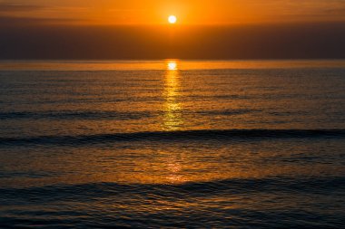 Deniz manzarasında turuncu gün batımının manzarası