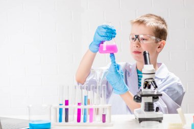 Mikroskobu olan bir öğrenci test tüplerindeki kimyasalları inceliyor, deneyler yapıyor - beyaz arka planda bir portre. Laboratuvarda koronavirüs incelemesi konsepti