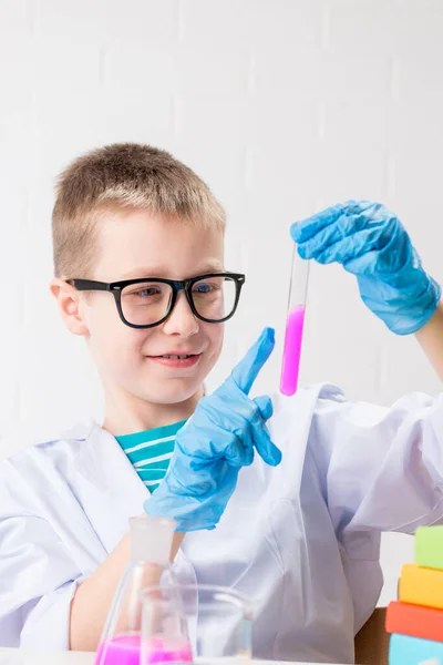 一个男孩在试管中学习多种颜色的物质 进行实验 白色背景的肖像 化验室中的头孢病毒研究概念 — 图库照片