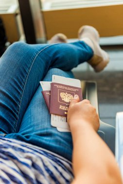 Havaalanında elinde pasaport ve biniş kartı olan bir kadın var.