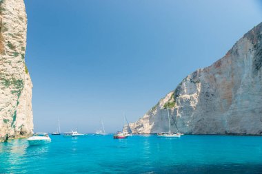 Turkuaz suyu, yatı ve kayaları olan güzel bir sahil.