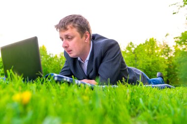 çim üzerinde yalan laptop ile çalışan adam