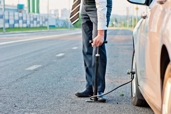 Mann im Business-Anzug pumpt Handpumpe Rad eines Autos — Stockfoto