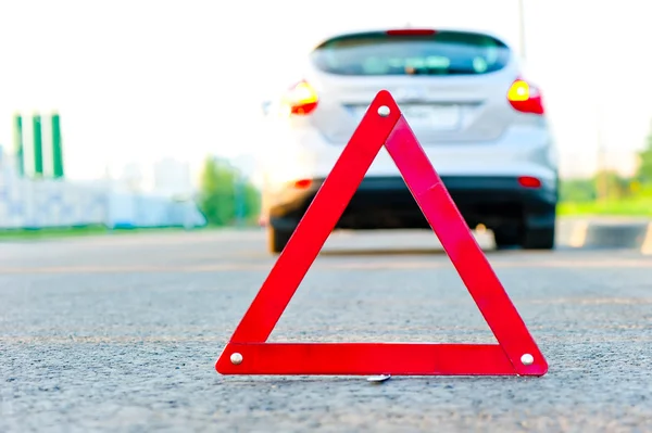 Triángulo rojo de advertencia y un coche con alarma de emergencia — Foto de Stock