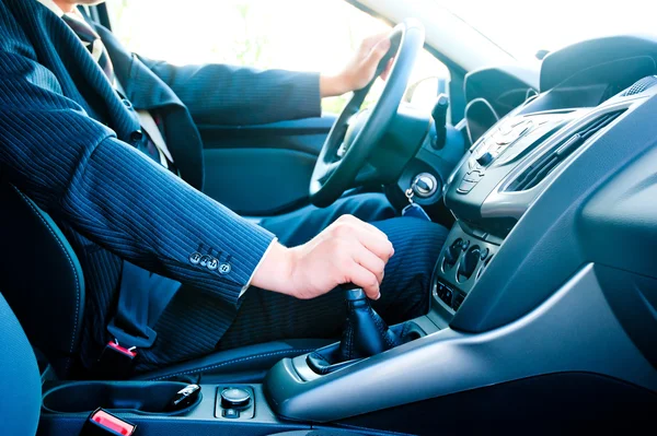 Een man in een pak in de auto veranderingen versnelling — Stockfoto