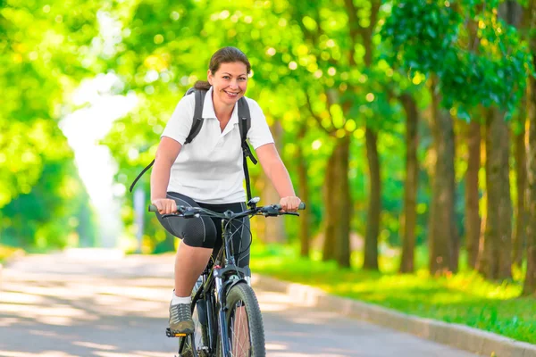 Joyful girl on a bicycle with a backpack — Stock Photo, Image