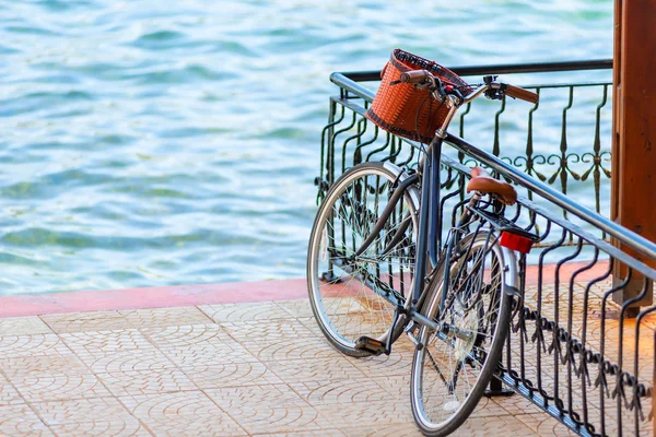 Zwarte fiets met een mand in de buurt van het hek op de pier — Stockfoto