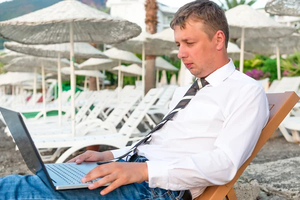 Manager arbetar på en bärbar dator på stranden — Stockfoto