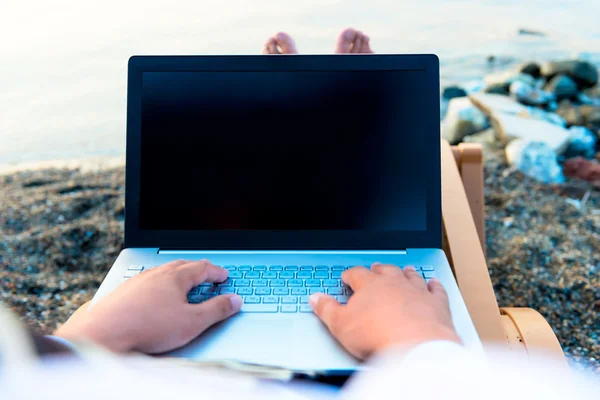 Ноутбук на коленях у моря — стоковое фото