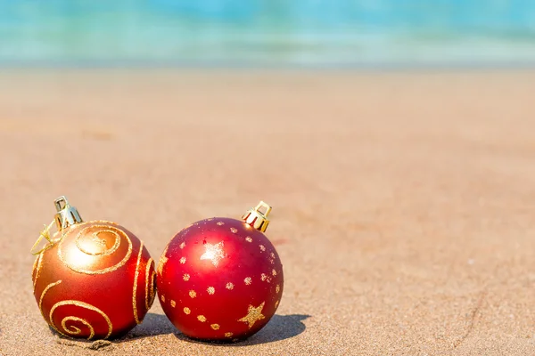 Два красных рождественских мяча на пляже — стоковое фото