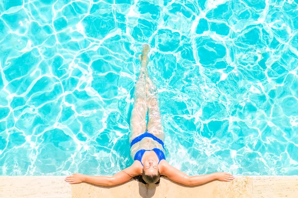 Vrouw ontspant aan de rand van het zwembad — Stockfoto