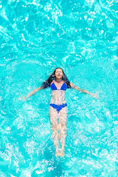 Girl in a blue swimsuit floating on his back — Stock Photo, Image