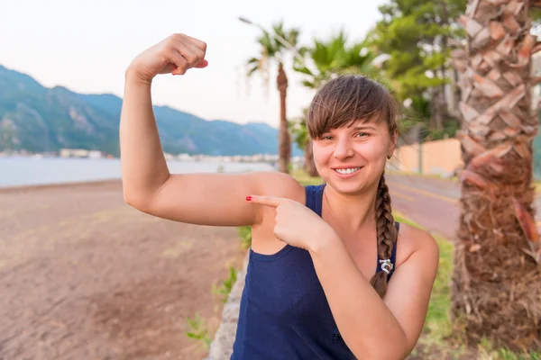 Athlète féminine souriant et montrant ses biceps — Photo