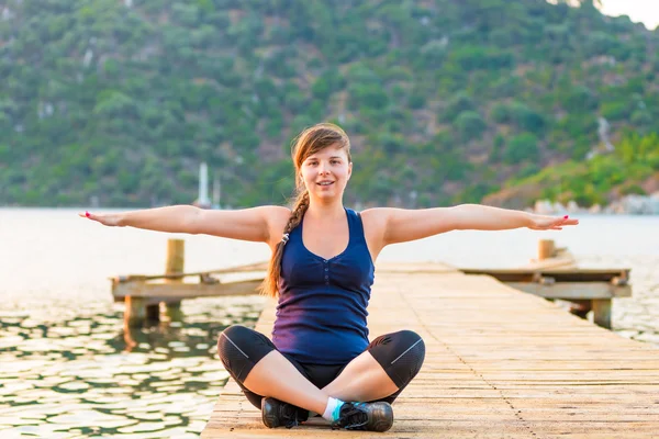 Entspanntes Mädchen auf einem Pier in der Lotusstellung — Stockfoto