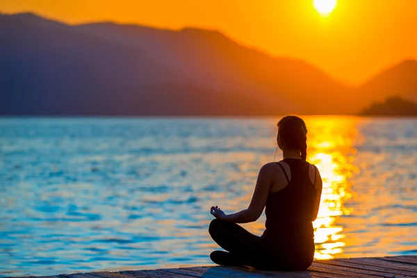 Chica en posición de loto admirando el sol naciente — Foto de Stock