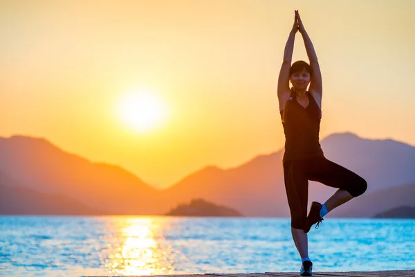 Pilates junto al mar. Niña equilibra al amanecer — Foto de Stock