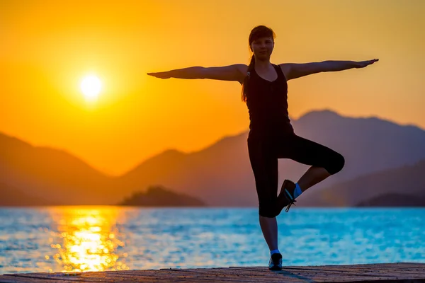 Утренняя йога у моря на фоне гор — стоковое фото