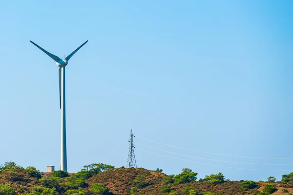 Moinho de vento e linha de energia na colina — Fotografia de Stock