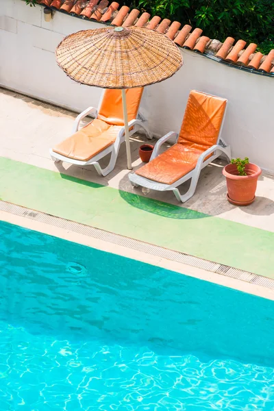 Lettini e ombrelloni vicino alla piscina — Foto Stock