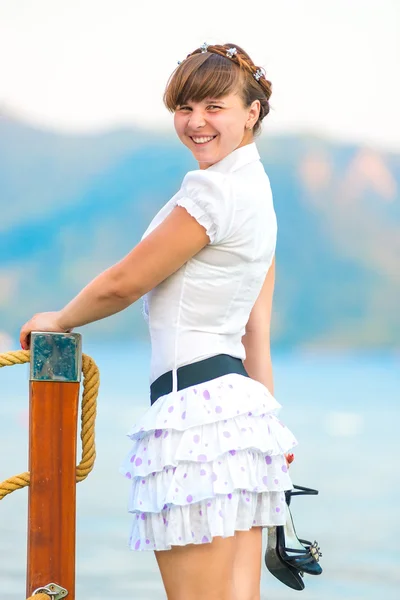 Ragazza allegra con le scarpe in mano sul molo — Foto Stock