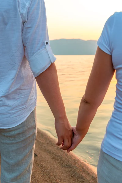 Couple holding hands on the shore — Stock Photo, Image