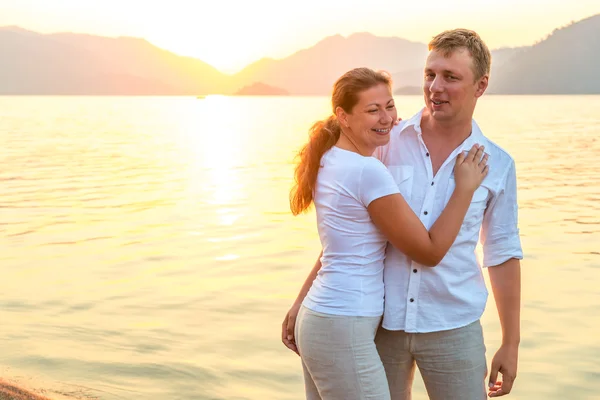 Casal feliz perto do mar ao nascer do sol — Fotografia de Stock