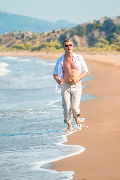 Male clothed in linen, runs along the seashore — Stock Photo, Image