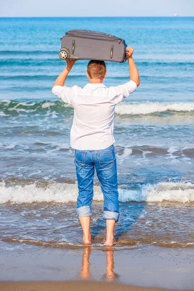 Man med en resväska går till havet — Stockfoto