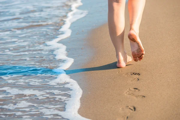 Piernas femeninas bien formadas dejan huellas en una playa de arena —  Fotos de Stock