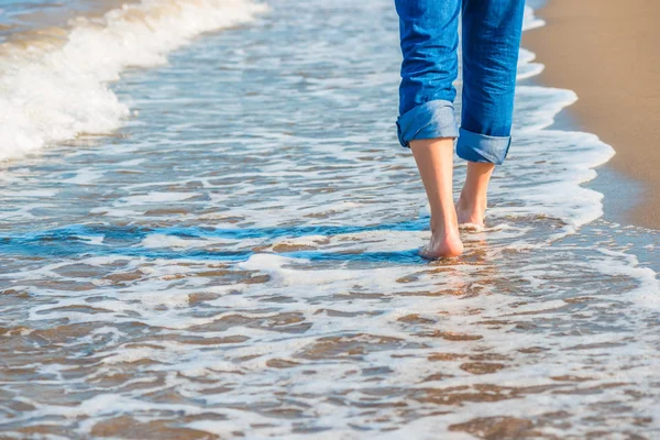 Manliga ben i jeans går längs sandstranden — Stockfoto