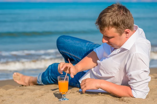 Framgångsrik ung man vila vid havet med cocktail — Stockfoto