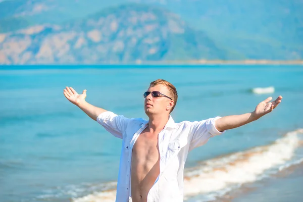 Successful man in the background of the sea with arms outstretch — Stock Photo, Image