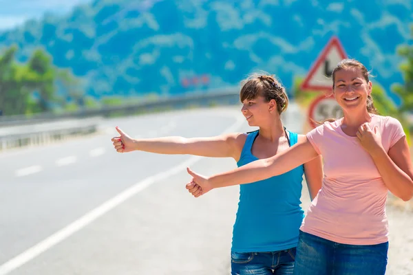 Funny young girl hitchhiking in the mountains — Stock Photo, Image