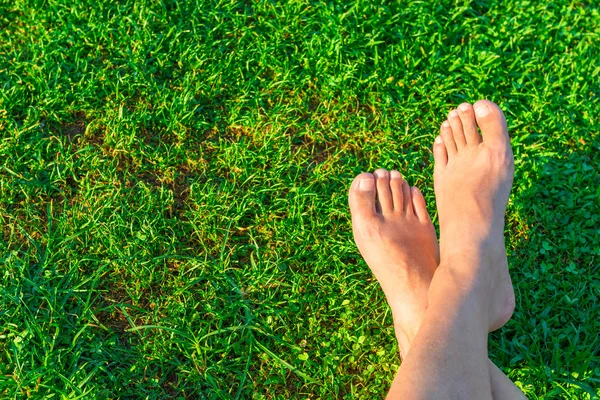 Los pies de los hombres en el fondo de la hierba verde exuberante — Foto de Stock