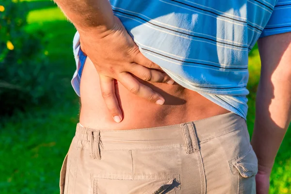 Mann hält sich die Hand wund am unteren Rücken — Stockfoto