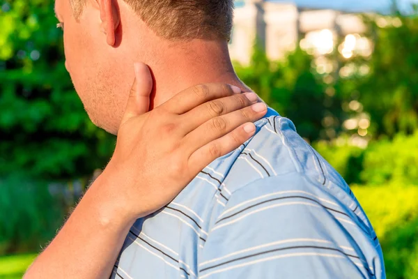 Male massaging sore shoulder outdoors — Stock Photo, Image