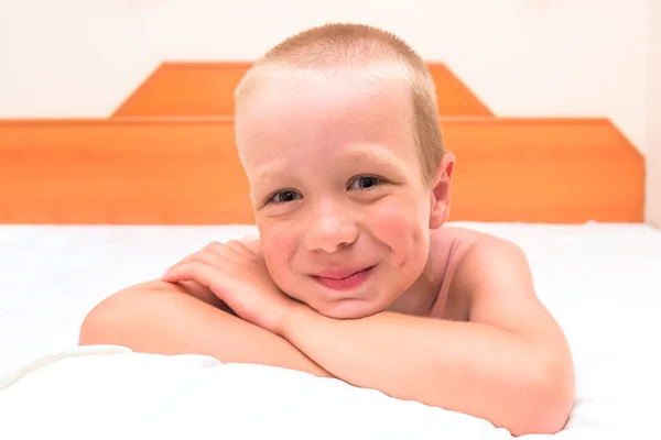 Mischievous preschooler resting in bed and smiling — Stock Photo, Image