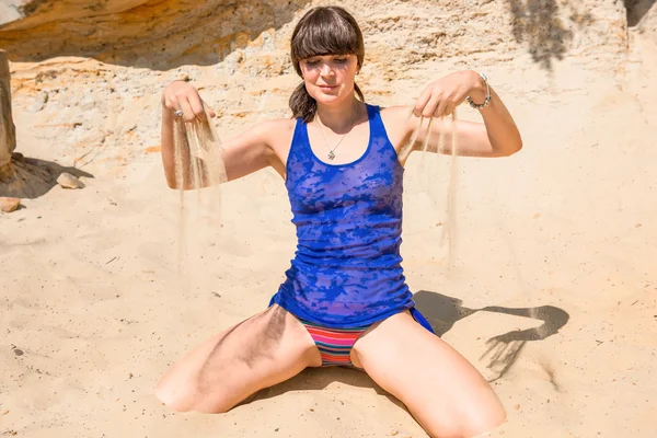 Mooie brunette spelen met zand op het strand — Stockfoto
