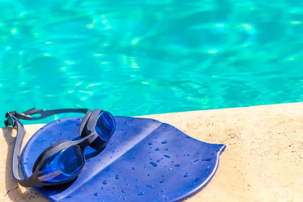 Колпачок и очки на краю бассейна — стоковое фото