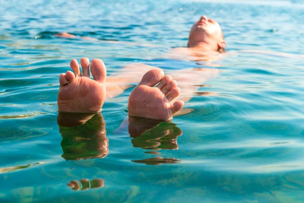 Voeten met gespreide vingers liggend op de watermens — Stockfoto