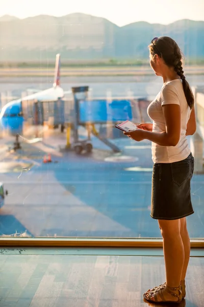 Fille regarde à travers le verre dans l'avion — Photo