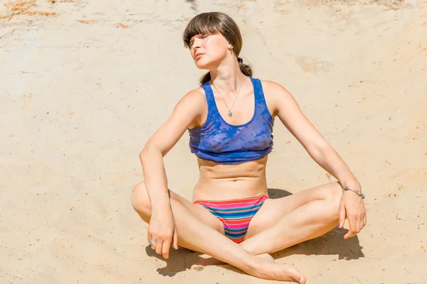ロータスの位置の砂の上で日光浴若くてきれいな女性 — ストック写真