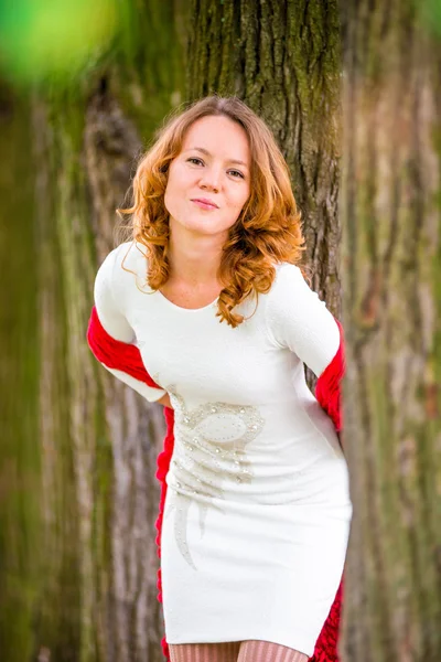 Red-haired girl in white dress among the trees — Stock Photo, Image