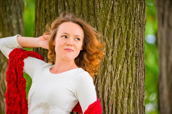 Retrato de una niña sobre un fondo de un árbol mirando hacia un lado — Foto de Stock