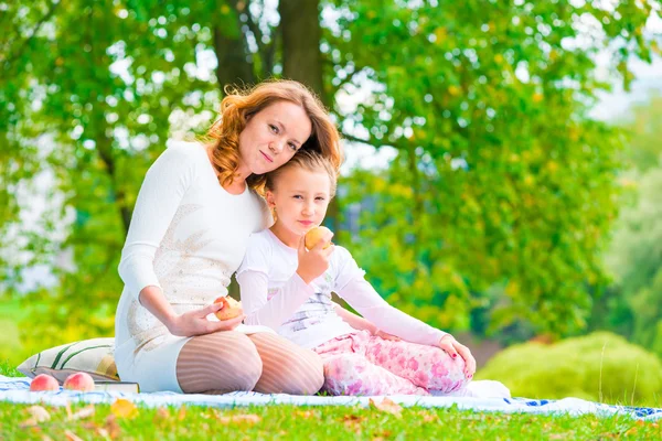 Gelukkige familie op een picknick snack appels in het park — Stockfoto