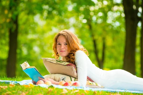 Retrato de um belo estudante em um parque de verão com um livro — Fotografia de Stock